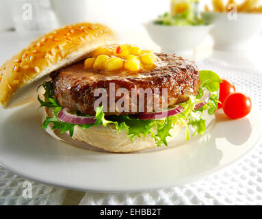 Burger de boeuf avec dans un petit pain avec de la salade, des frites et de la relish de maïs Banque D'Images