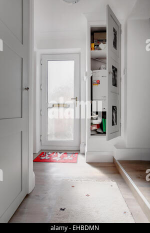 À l'intérieur d'une maison au Royaume-Uni avec un décor moderne montrant une porte menant à l'extérieur et placard porte ouverte montrant chaudière. Banque D'Images