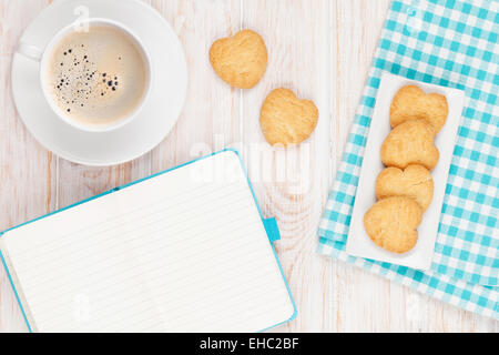Café, biscuits en forme de coeur et le bloc-notes sur la table en bois blanc, avec copie espace Banque D'Images