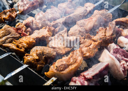 Préparation d'agneau grillées traditionnelle connue sous le nom de shish kebab ou des brochettes. La viande, la fumée et le charbon de la chaleur. Banque D'Images