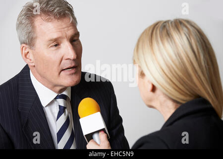 Businessman Interviewée par femme journaliste avec microphone Banque D'Images