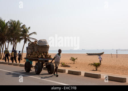 Lomé, Togo, 9 décembre 2012 ; un garçon tire un panier de cocotiers le long du bord de route. Banque D'Images