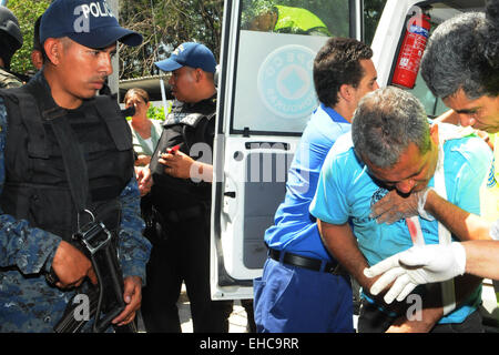 San Pedro Sula, au Honduras. Mar 11, 2015. Policiers honduriens une garde prisonnier blessé qui reçoit un traitement médical dans un hôpital public après une mutinerie des prisonniers dans le centre pénitentiaire de San Pedro Sula, dans le nord du Honduras, le 11 mars 2015. Au moins trois personnes sont mortes et plus de 30 ont été blessés pendant le tournage le mercredi dans le centre pénitentiaire de San Pedro Sula, au cours d'une émeute contre le transfert des détenus d'autres prisons menées par les autorités du Honduras, selon la presse locale. Credit : Rafael Ochoa/Xinhua/Alamy Live News Banque D'Images