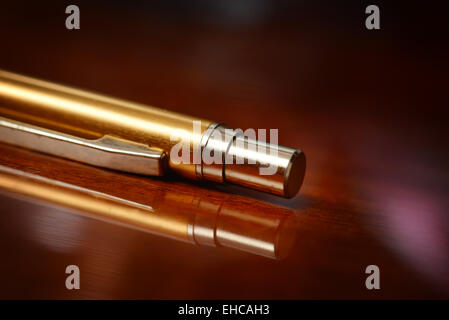 Plume d'or sur une surface en bois verni avec feux Banque D'Images