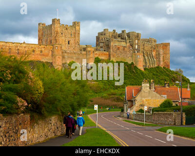 Les touristes à pied sur la route ci-dessous château de Bamburgh Northumberland England UK accueil de la famille Armstrong Banque D'Images