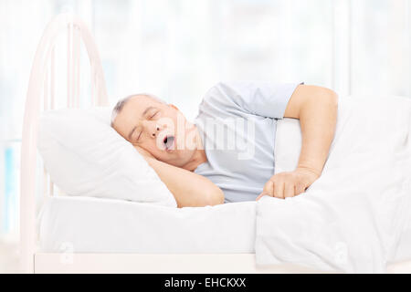 Homme mûr de dormir dans un lit confortable à la maison Banque D'Images