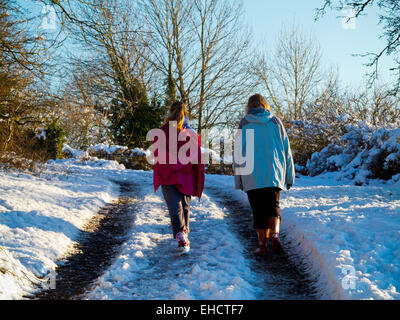 Femme et enfant marche sur un chemin couvert de neige près de Matlock dans le Peak District Derbyshire Dales England UK Banque D'Images