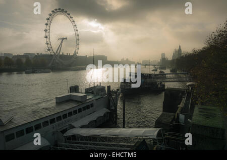 Vue brumeuse de la Tamise à Westminster, Londres, prise du Golden Jubilee Bridge, en regardant vers le London Eye. Bateaux en premier plan. Banque D'Images