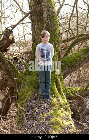 Jeune garçon debout sur un vieil arbre envahies par la mousse, Elbe, Riverside, Sandkrug Schnakenbek, Schleswig-Holstein, Allemagne Banque D'Images