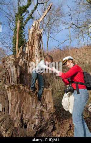 Mère d'aider son jeune fils sur une souche d'arbre au bord de l'Elbe près de Sandkrug, Schnakenbek, Schleswig-Holstein, Allemagne Banque D'Images