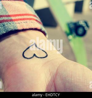 Libre du poignet d'un jeune homme avec un coeur tatoué dans c Banque D'Images