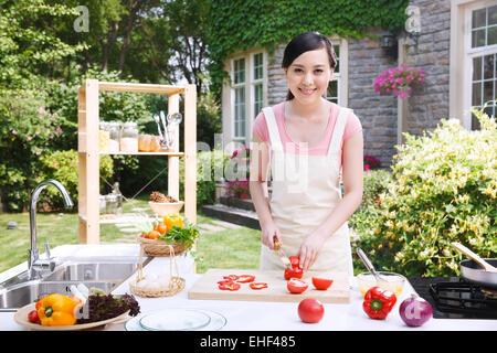 Une femme orientale en cuisine extérieure hacher les légumes Banque D'Images