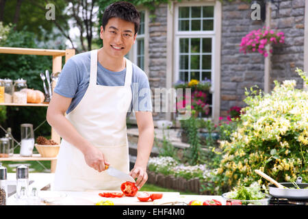 Homme de famille dans cuisine extérieure hacher les légumes Banque D'Images