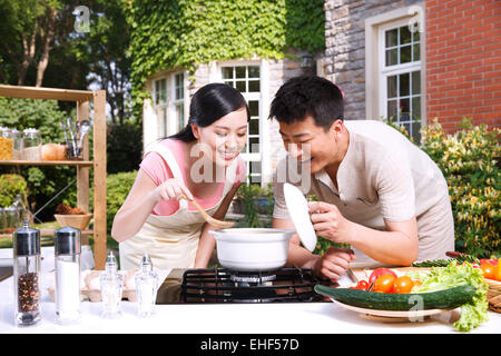 Le jeune couple de goûter la soupe dans la cuisine Banque D'Images