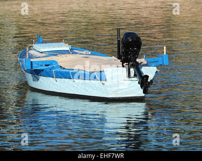 Petit bateau en bois avec moteur hors bord flotte à travers les vagues du lagon bleu Banque D'Images