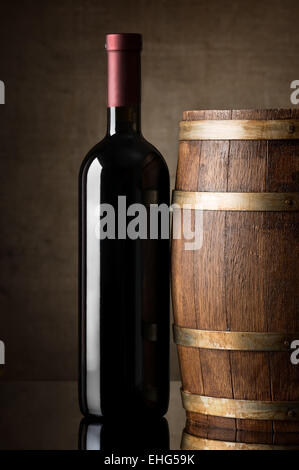 Vin rouge dans une bouteille près de tonneau en bois Banque D'Images