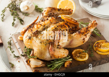De Citron et d'herbes de la maison du poulet entier sur une planche à découper Banque D'Images