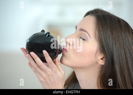 Woman putting coins into a piggy bank Banque D'Images