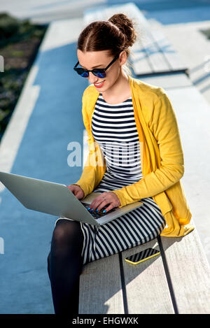 Woman with laptop and phone outdoors Banque D'Images