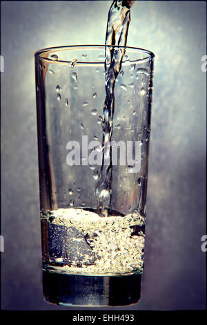 Verser le liquide dans le verre sur grunge fond.tonique de l'image. Banque D'Images