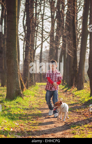 Boy and dog walking in park Banque D'Images