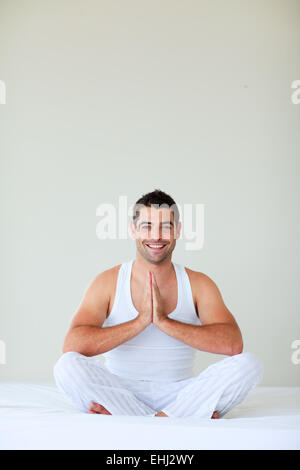 Jeune homme faisant du yoga dans sa chambre à coucher Banque D'Images