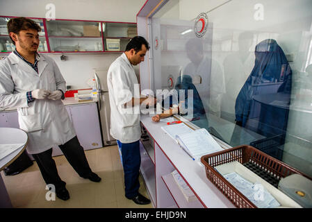 Gestionnaire de laboratoire Hekmatullah Sadate attire le sang de femme portant burqa pour prise de sang en laboratoire de l'hôpital central de la Société afghane du Croissant-Rouge, Kaboul, Afghanistan Banque D'Images