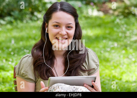 Jeune femme avec tablet PC dans un jardin Banque D'Images