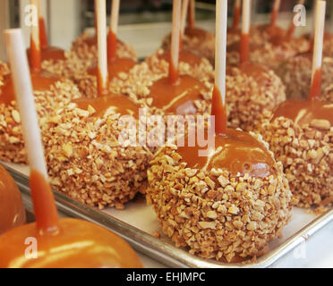 Un bac de caramel et de pommes enrobées d'arachide et à des bâtonnets. Banque D'Images