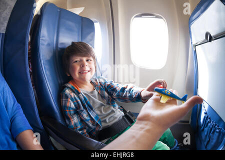 Laughing boy prendre avion jouet, s'asseoir sur avion à réaction Banque D'Images