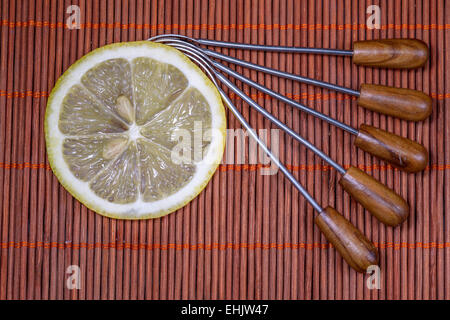 Citron frais tranchés avec la fourche sur un joli tapis en osier comme arrière-plan Banque D'Images