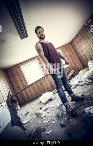 Un jeune homme, redneck / punk rocker nettoyer après partie, sale et malpropre chambre.. Banque D'Images