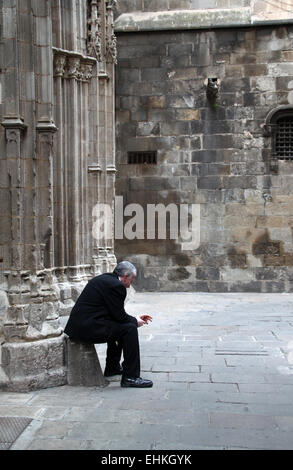 Homme assis seul derrière la cathédrale dans le quartier gothique de Barcelone, Catalogne, Espagne Banque D'Images