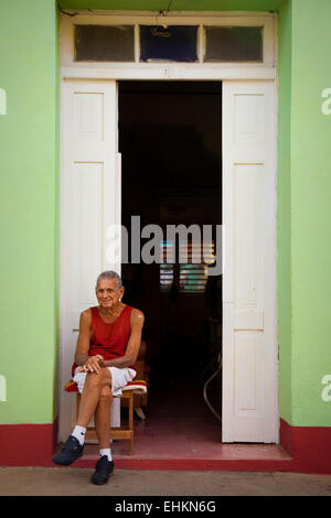 Un vieil homme est assis dans l'embrasure d'une porte à Trinidad, Cuba Banque D'Images