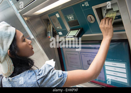 Jeune femme achète un distributeur automatique de billets Banque D'Images