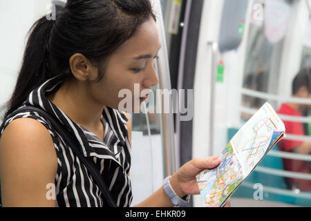 Femme assise dans un train et étudie la route carte Banque D'Images