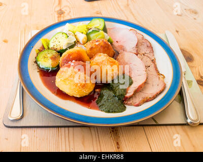 English Le dimanche midi l'agneau rôti brocoli poireaux et sauce servi avec sauce à la menthe sur une plaque bleu et blanc table en bois Banque D'Images