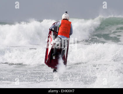 Homme jet ski concurrent exécute l'action de l'antenne se déplace dans de grandes vagues déferlantes sur la plage de Fistral Newquay Banque D'Images