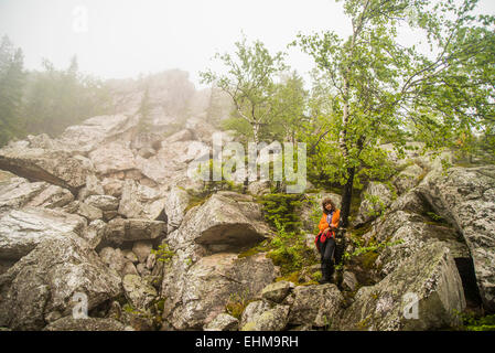 Caucasian hiker comité permanent en vertu de l'arbre sur la colline rocheuse Banque D'Images