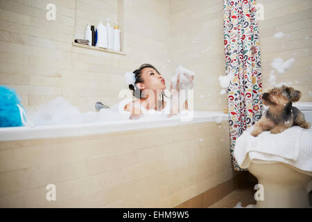 Chinese Woman Playing with dog in bubble bath Banque D'Images