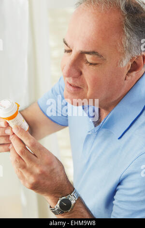 Hispanic man reading médicament de prescription bottle Banque D'Images