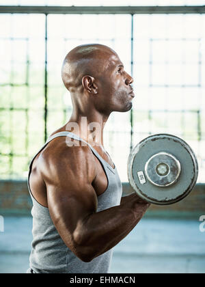 Black man lifting weights in warehouse Banque D'Images