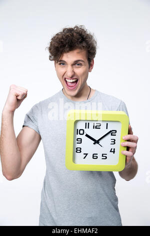 Happy man holding horloge avec bras levés sur fond gris Banque D'Images