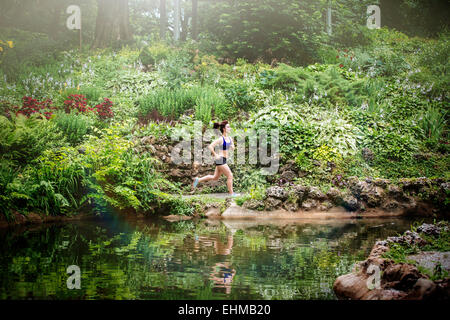 Caucasian woman running in park près du lac Banque D'Images