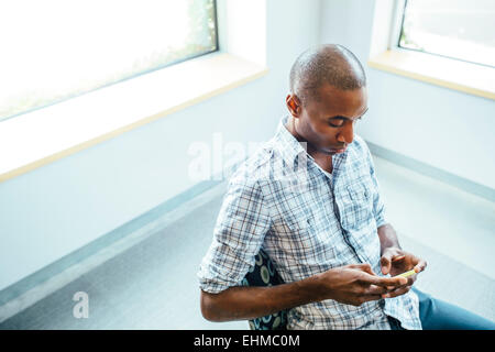 Black man using cell phone in office Banque D'Images