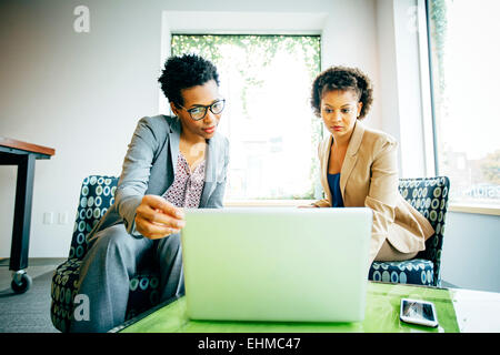 Businesswomen using laptop in office lobby Banque D'Images