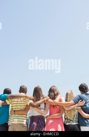 Vue arrière d'adolescents hugging under blue sky Banque D'Images