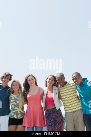 Les adolescents souriants hugging under blue sky Banque D'Images