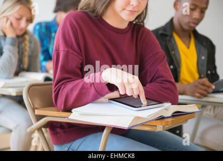 Teenage student sitting on desk in classroom Banque D'Images