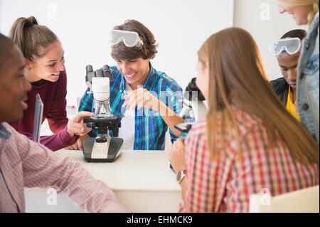 Teenage students using microscope in science laboratory Banque D'Images